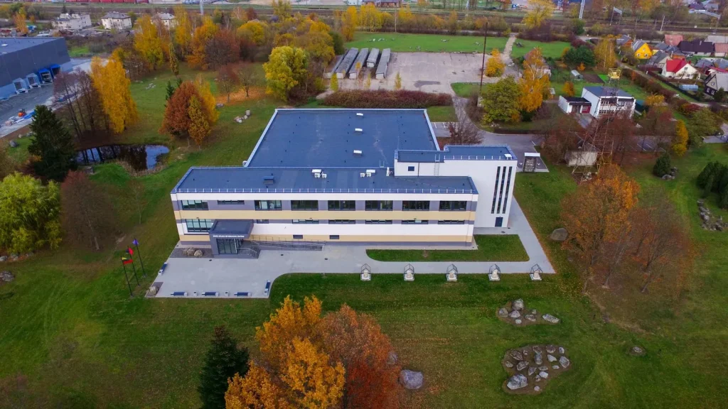 Ilgas pastatas mėlynu stogu rudens parke, iš drono